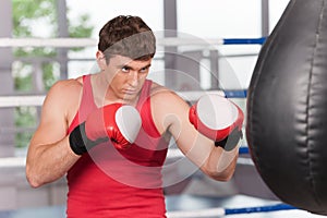 Boxer doing some training on punching bag at gym.