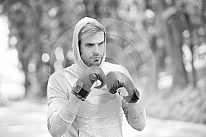 Boxer exercise on fresh air. Knowckout. Man punching. Fight for success. Man in boxing gloves and hood on natural