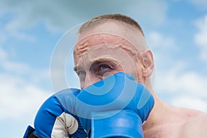 Boxer fighter training outdoors. Sportsman muay thai boxer fighting in gloves. Sporty man during boxing exercises. Man