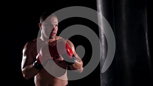 Boxer man during boxing hiting heavy bag at