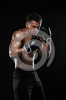 Boxer, man fighting or posing in gloves on black background. Fitness and boxing concept. Individual sports recreation.