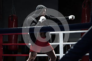Boxer man workout in boxing ring. Boxing fighter in hoodie