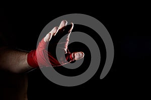 A boxer`s red bandage on his hand isolated on dark blurred background, close-up.