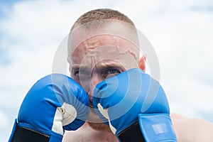 Boxer training outdoor. Closeup portrait of male boxer training defense and attacks in boxing gloves.