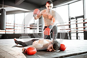 Boxer winner with beaten man on the boxing ring