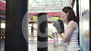 Boxer woman doing some workouts on a punching bag in the gym.Close up