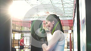 Boxer woman doing some workouts on a punching bag in the gym.Close up slow mo