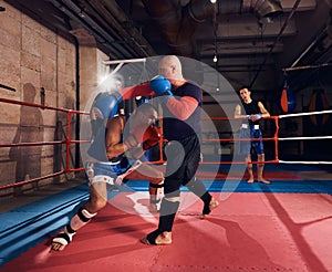 Boxers training kickboxing in the ring at the health club