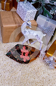 boxes with Christmas gifts under the blue Christmas tree, in foreground a bouquet of chocolate flowers