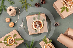 Boxes, craft paper, twine, scissors, dried oranges and natural decor for wrapping XMAS, New Year gifts on green background.