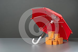 Boxes with goods under a red umbrella. Cargo and parcel insurance.