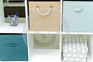 Boxes and organizers in a white office cabinet. Bright office in blue and beige tones