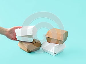 Boxes for packing sandwiches on a blue background, human hands. Place for text and logo. The concept of food, delivery