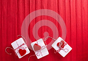 Boxes with presents with hearts  on  red textured  paper background.