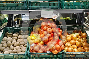 Boxes with ripe fresh potatoes and onions on shelves