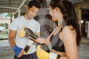 a boxing coach helping the female boxer to wearing the boxing gloves