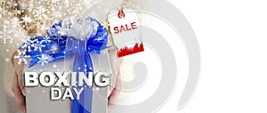 Boxing day sale concept of young woman hands holding silver gift