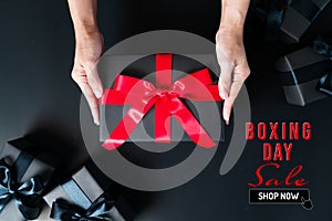 Boxing Day sale, woman hand give the gift box on black background