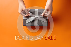 Boxing Day sale, young woman hand with a gift box offer to receiver