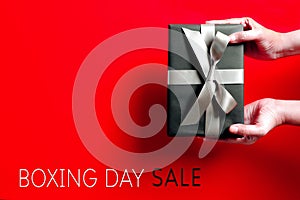 Boxing Day sale, young woman hand with a gift box offer to receiver