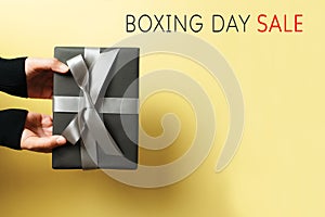 Boxing Day sale, young woman hand with a gift box offer to receiver