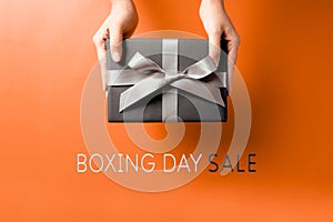 Boxing Day sale, young woman hand with a gift box offer to receiver