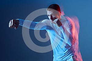 Boxing exercises. Right kick. Male athlete in white sportswear doing box exercises in studio on blue background.
