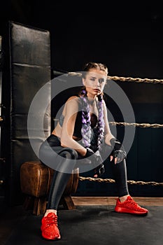 Boxing fashion girl on break sits on a chair resting in a boxing competition ring.