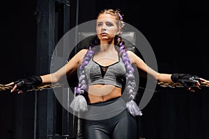 boxing girl stands leaned on ropes of competition ring.