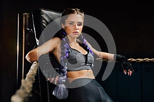 boxing girl stands leaned on ropes of competition ring.