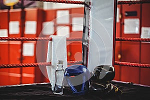 Boxing gloves, headgear, water bottle and a towel in boxing ring