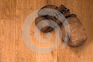 Boxing gloves. Old vintage retro pair of leather worn mittens are on the wood table. Red colors and soft lights