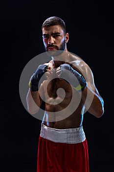 Boxing man ready to fight. Boxer with strong hands and clenched fists in blue straps against a black background