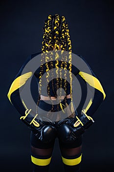 Boxing sport concept. Woman with yellow braids on black background. Girl sportsman muay thai boxer fighting in gloves in