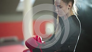 Boxing training - an attractive young woman puts on red boxer gloves