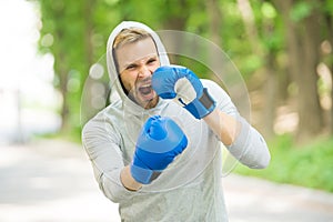 Boxing training endurance. Man athlete concentrated face with sport gloves practicing boxing nature background. Boxer