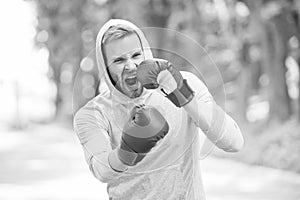 Boxing training endurance. Man athlete concentrated face with sport gloves practicing boxing nature background. Boxer