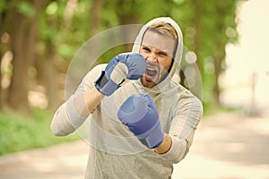 Boxing training endurance. Man athlete concentrated face with sport gloves practicing boxing nature background. Boxer