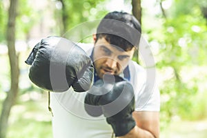 Boxing training endurance. Man athlete concentrated face with sport gloves practicing boxing nature background. Boxer ready to