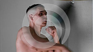 Boxing training - shirtless young man punching a small punching bag in front of his face