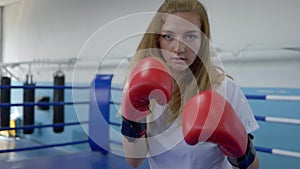 Boxing training, sportswoman works out boxer strikes at camera on ring