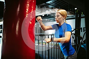 Boxing training woman with punching kicking bag in gym