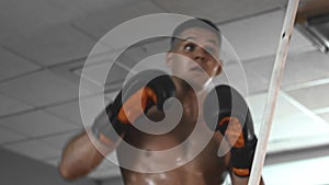 Boxing training - young man fighting against a training stick in a gym