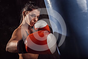 Boxing. Woman boxer in gloves exercise with punching bag hitting concentrated close-up