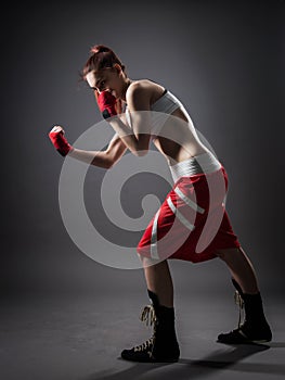 Boxing woman during exercise-gray background