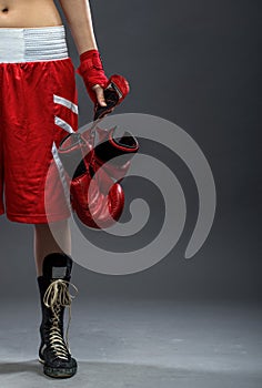 Boxing woman standing in box dress, holding boxing gloves - half body photo