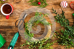 Boxwood Christmas wreath. DIY Christmas decoration concept. Wooden desk top view background.