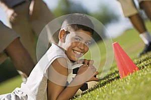 Boy (13-15) lying down on grass holding soccer ball.