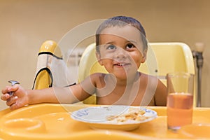 The boy 2 years eats meat. Children& x27;s table. The concept of the child& x27;s independence. Cute toddler boy with spoon is