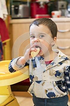 Boy 2 years old eating banana. Baby 2 years old eating a banana in the kitchen